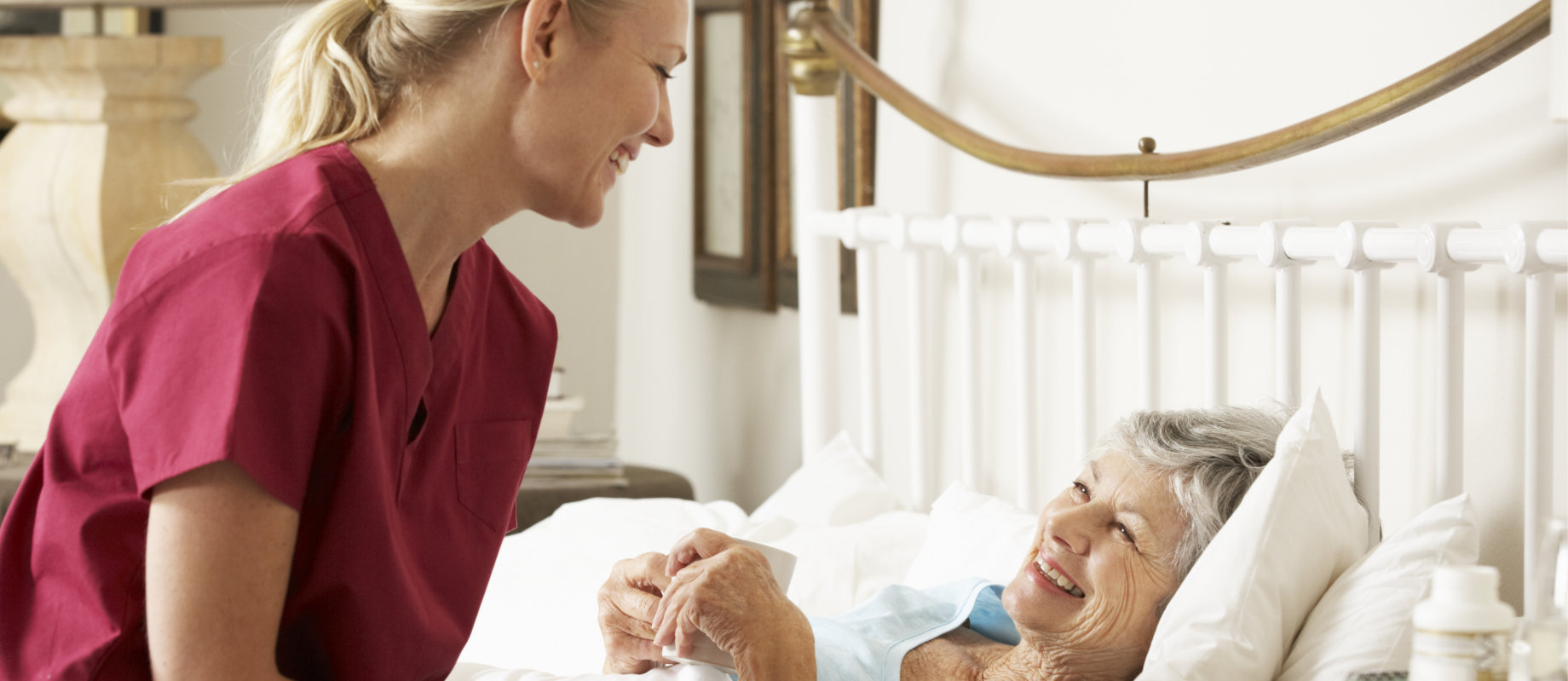 caregiver taking care of senior woman in bed